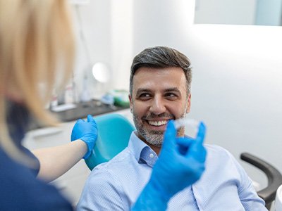 A young female dentist showing an Invisalign tray to her patient