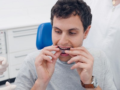 A young man putting Invisalign trays in his mouth