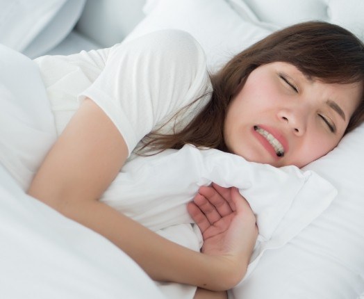 Sleeping woman clenching teeth before treatment for T MJ and bruxism treatment