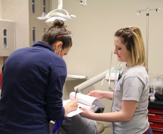 Two dental team members reviewing dental patient chart