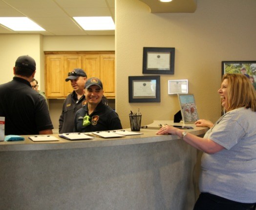 Firefighters behind dental office reception desk for community event