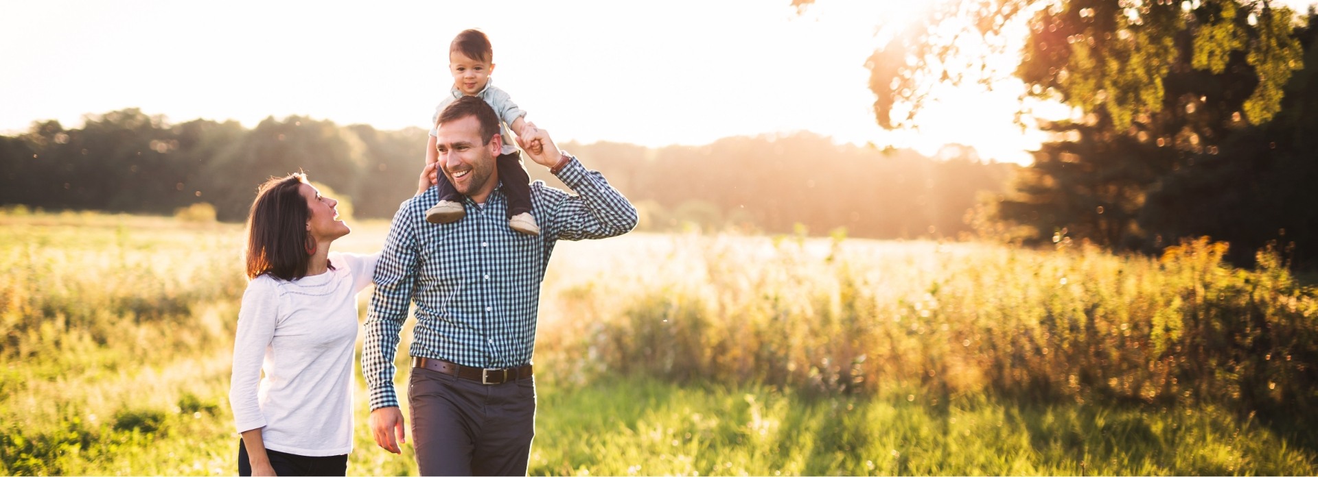 Family of three smiling together outdoors