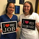 Two team members holding signs that say I love my job