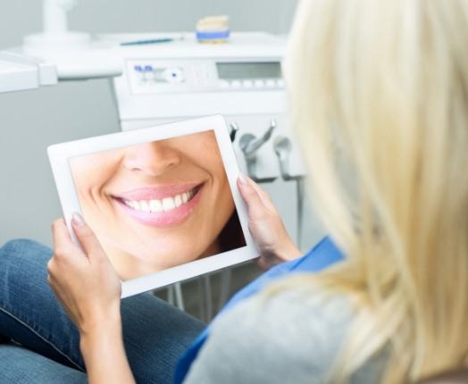 Woman looking at smile makeover option on tablet computer
