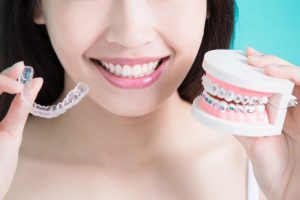 person holding Invisalign aligners and braces