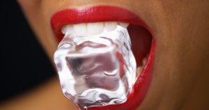 woman with red lipstick mouth open biting into ice