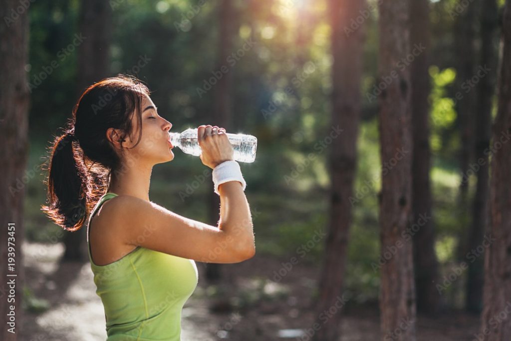 Woman drinking from her water bottle during the summer.