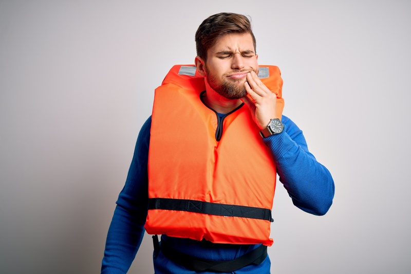 A man with a life jacket suffering a dental emergency