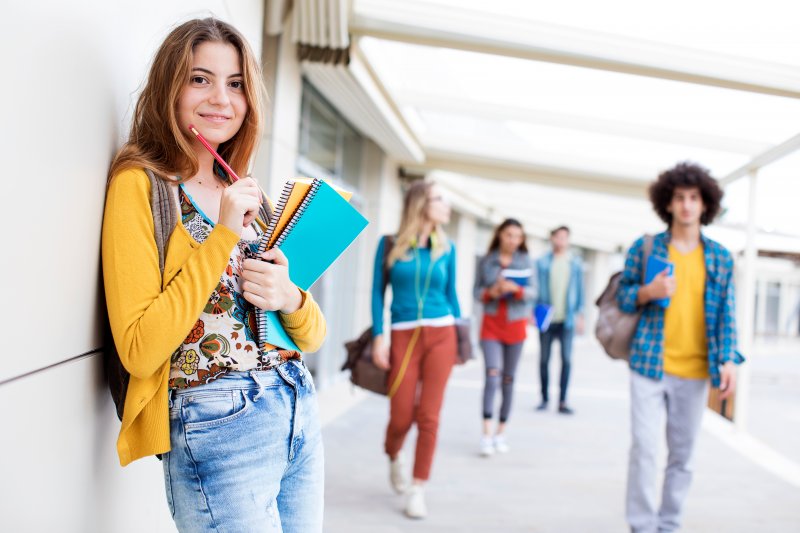 A smiling girl standing outside her school