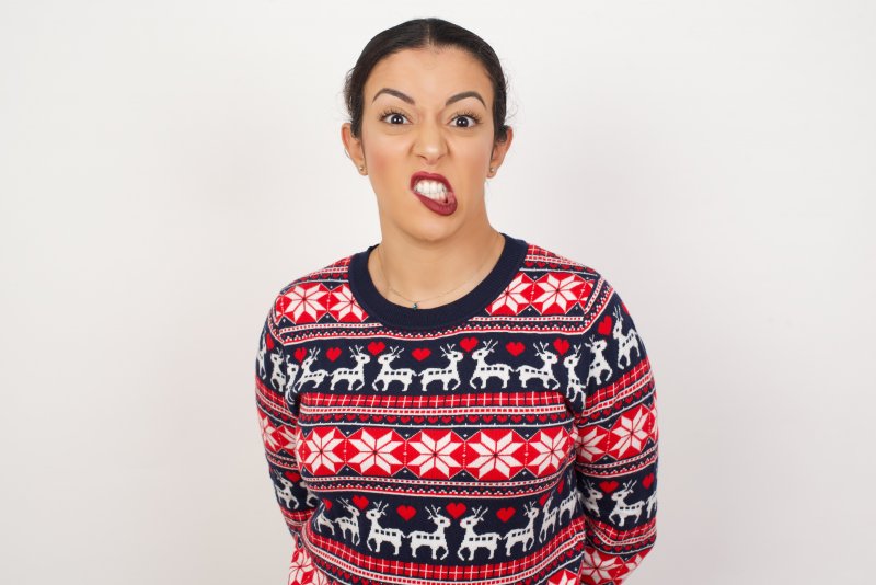 A grimacing woman wearing a holiday sweater