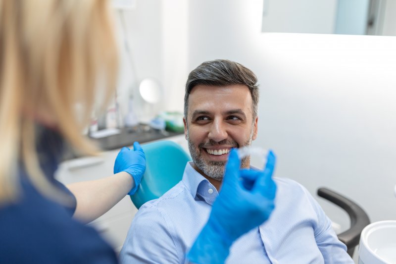 A dentist showing an Invisalign aligner to her patient