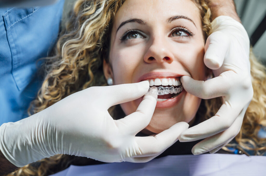 A woman having Invisalign trays put over her teeth